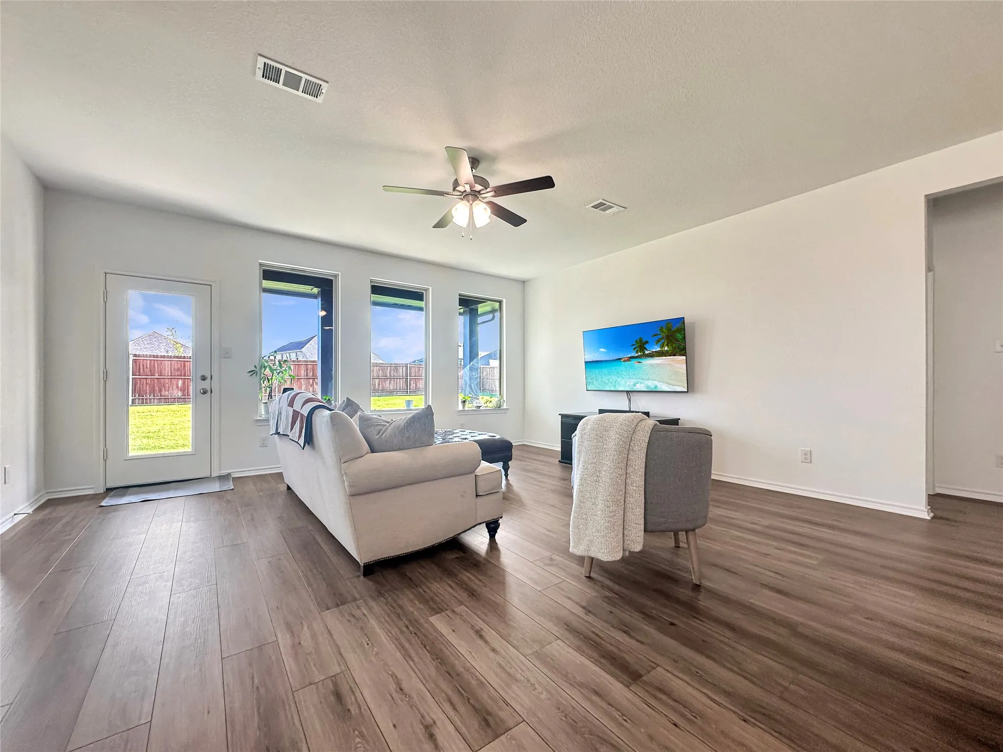 Living room with dark hardwood / wood-style flooring, a healthy amount of sunlight, and ceiling fan
