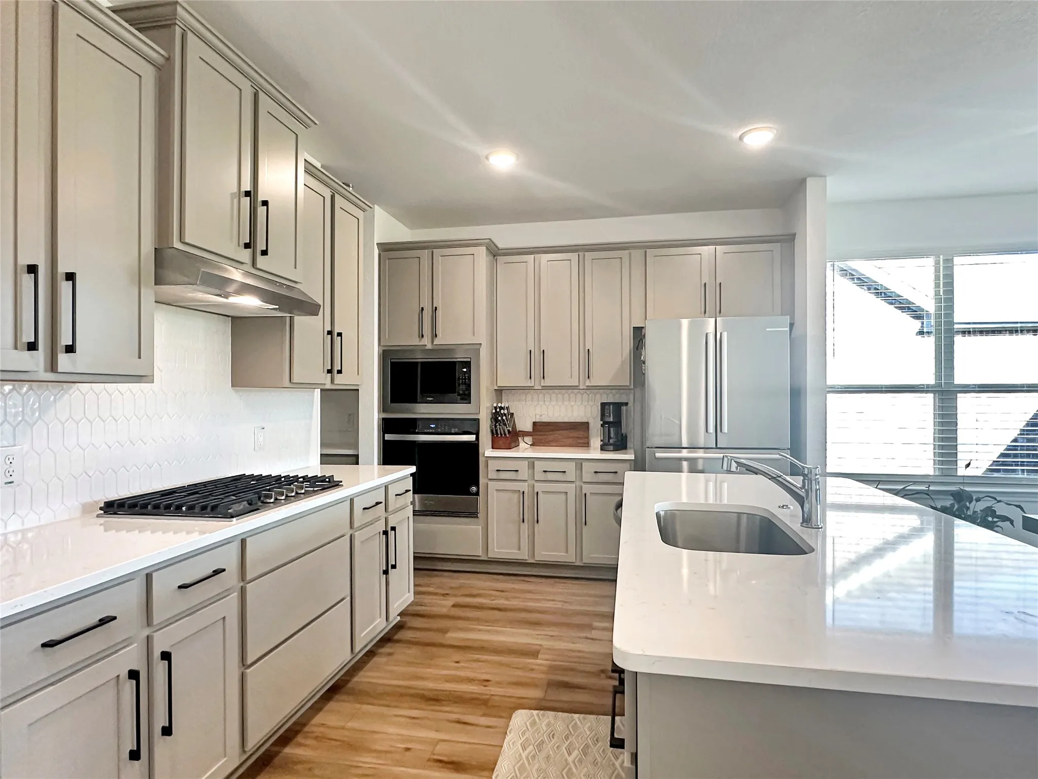 Kitchen with light hardwood / wood-style flooring, appliances with stainless steel finishes, gray cabinetry, and sink