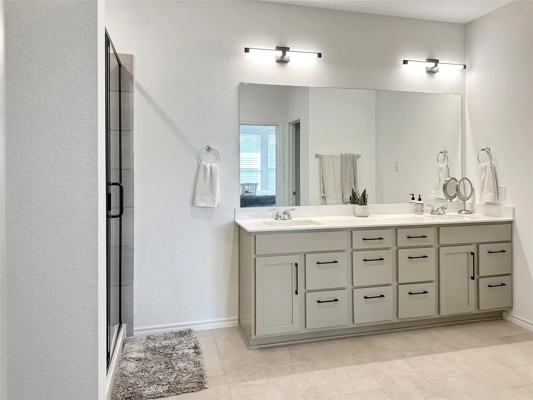 Bathroom with vanity, a shower with shower door, and tile patterned floors
