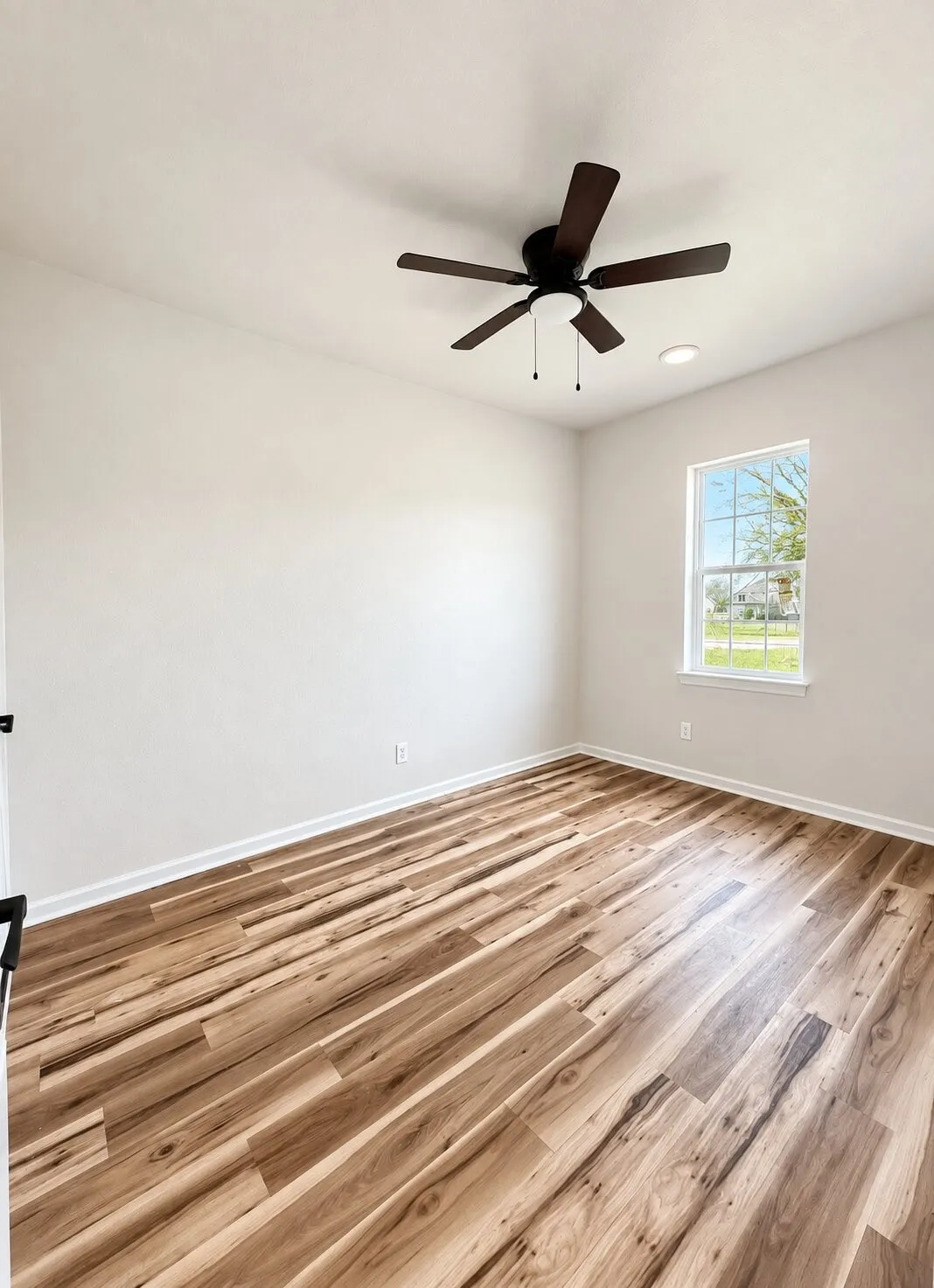Wood-finish flooring, white baseboards, and a ceiling fan with integrated lighting