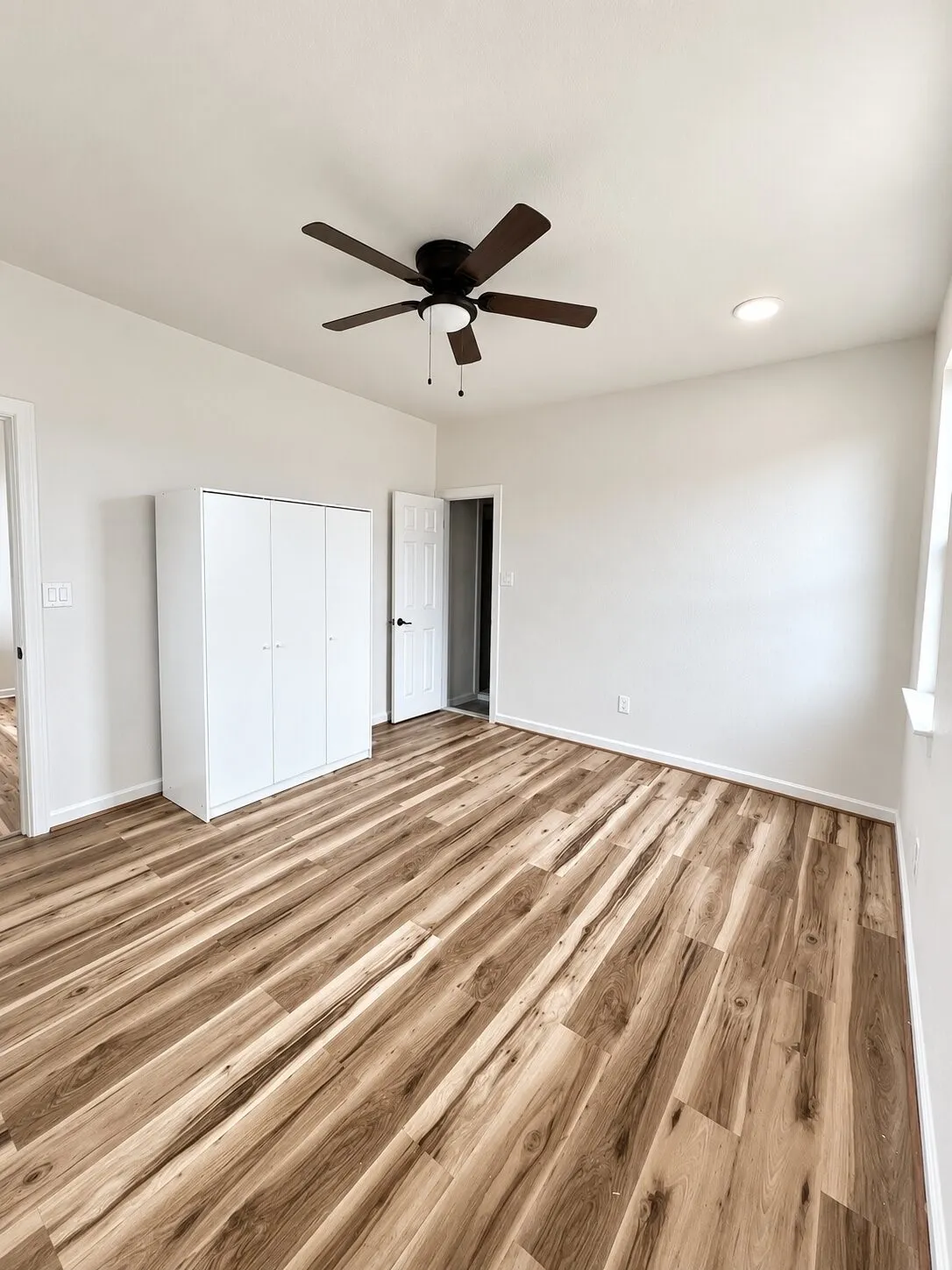 Wood-finish flooring, ceiling fan, recessed lighting, white trim