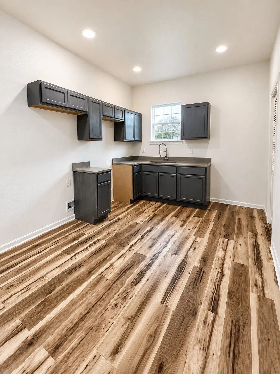 Dark cabinetry, wood-finish flooring, recessed lighting, and a double-hung window