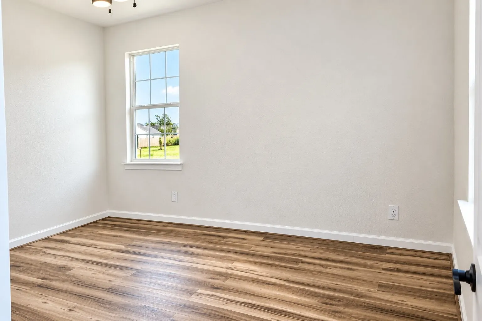 Wood-finish flooring, white walls, and a window with white trim