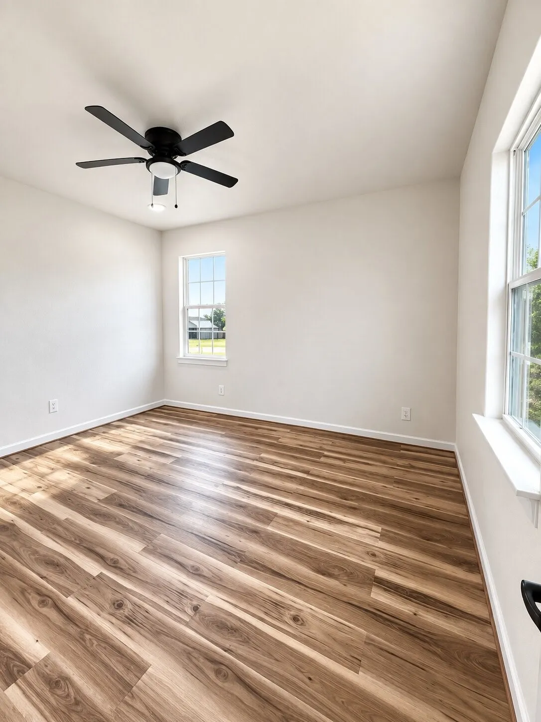 Wood-finish flooring throughout, multiple windows, and a ceiling fan with integrated lighting