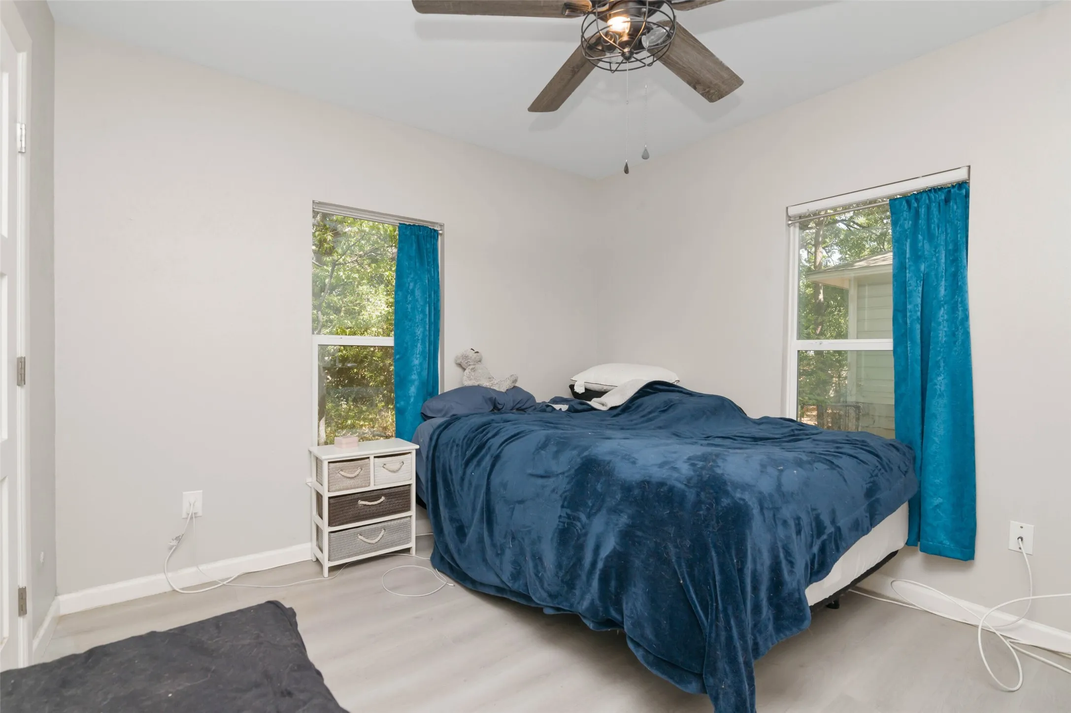 Wood-finish flooring with white walls and a ceiling fan with integrated lighting