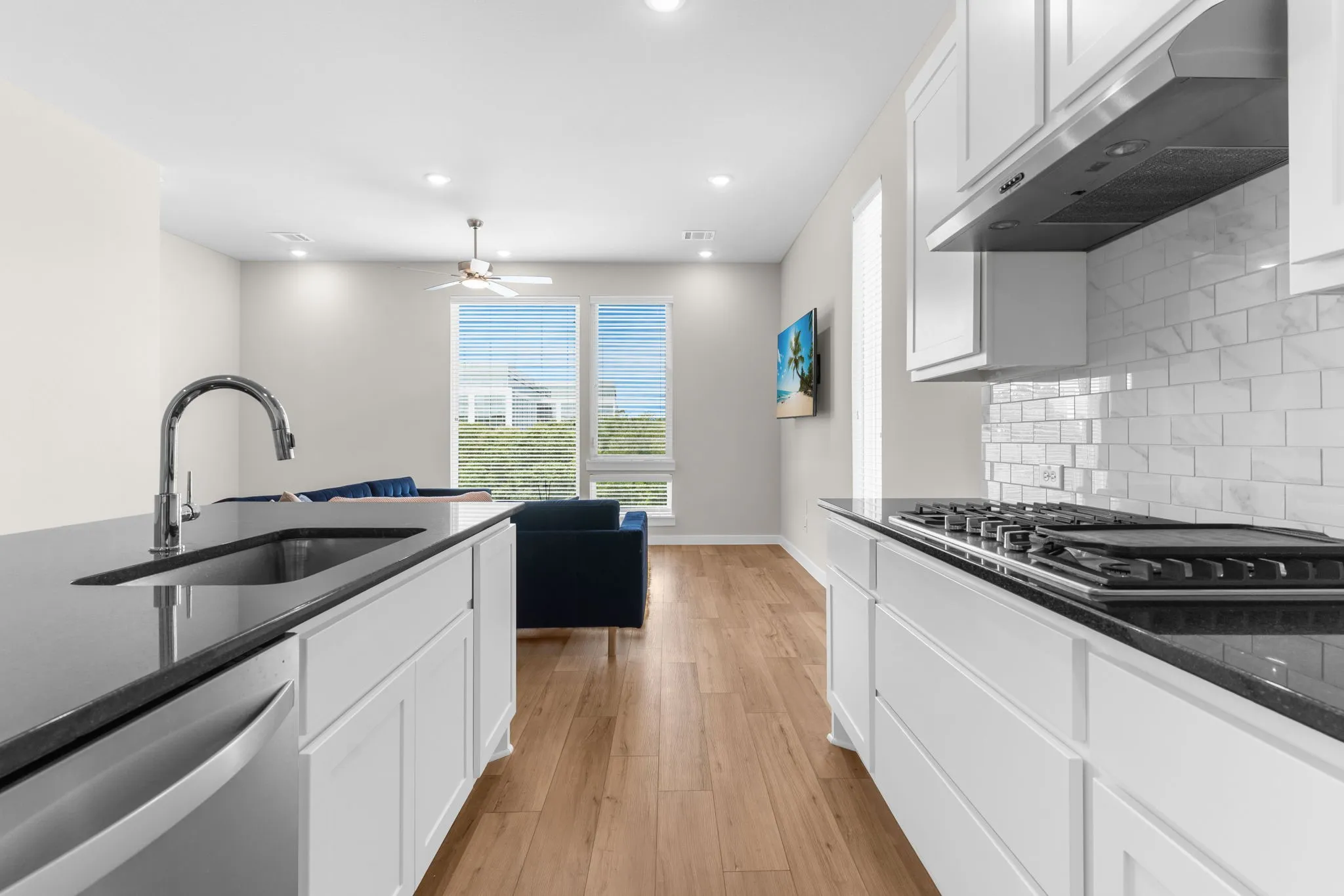 Contemporary kitchen featuring dark countertops, white cabinetry, a built-in gas range, stainless steel appliances, and subway tile backsplash