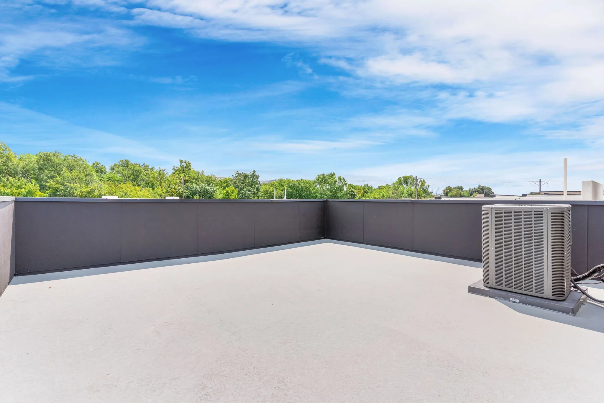 Expansive outdoor space featuring a light-colored surface and a dark perimeter wall