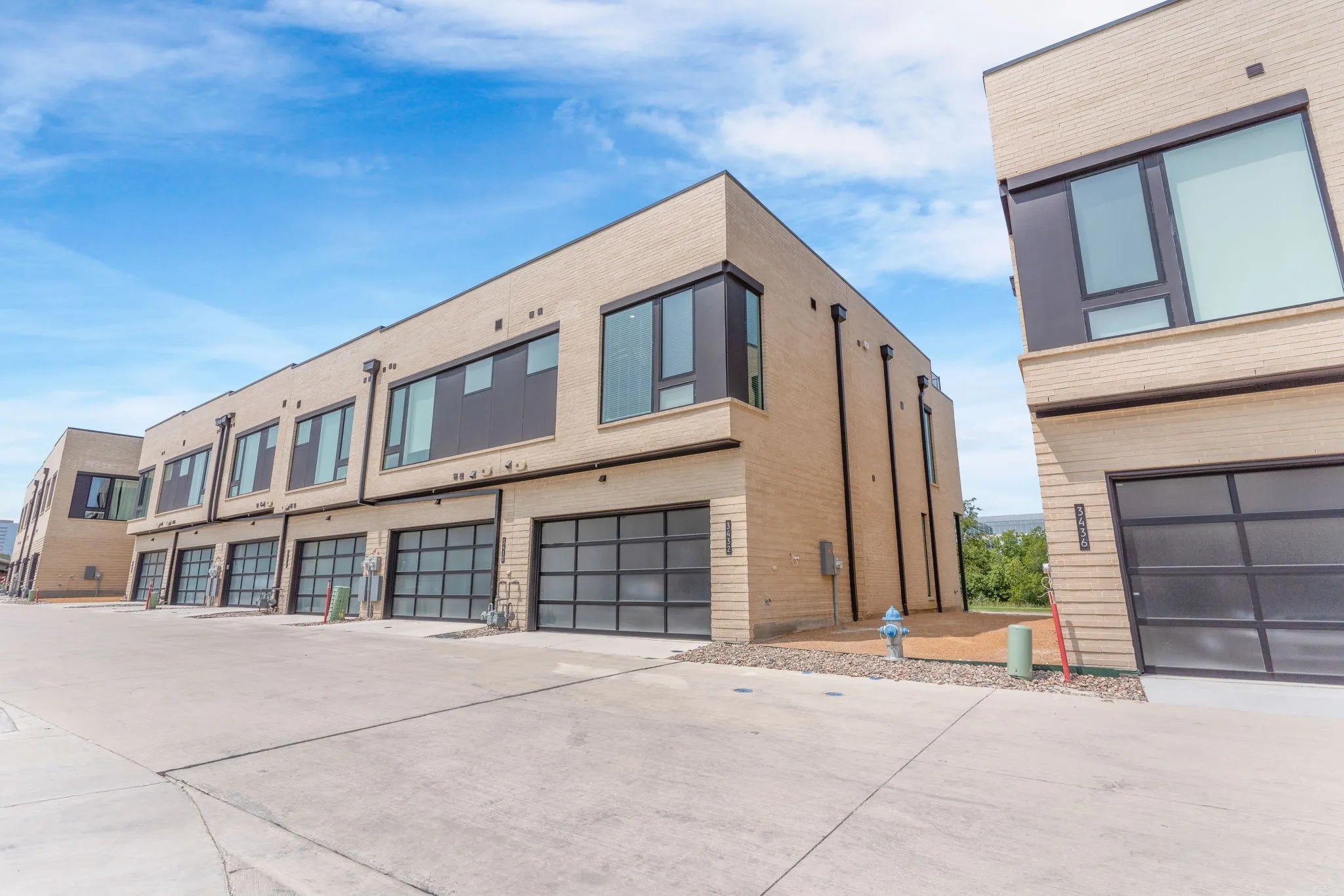 Modern townhome architecture featuring light-colored brick and dark-framed windows