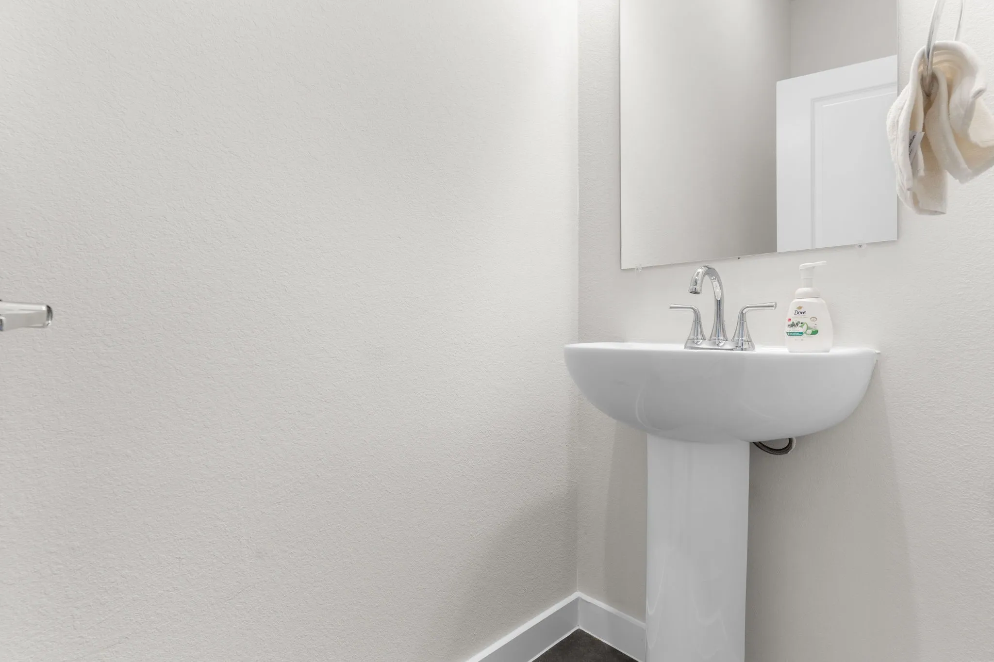 Pedestal sink with chrome-finish faucet and wall-mounted mirror