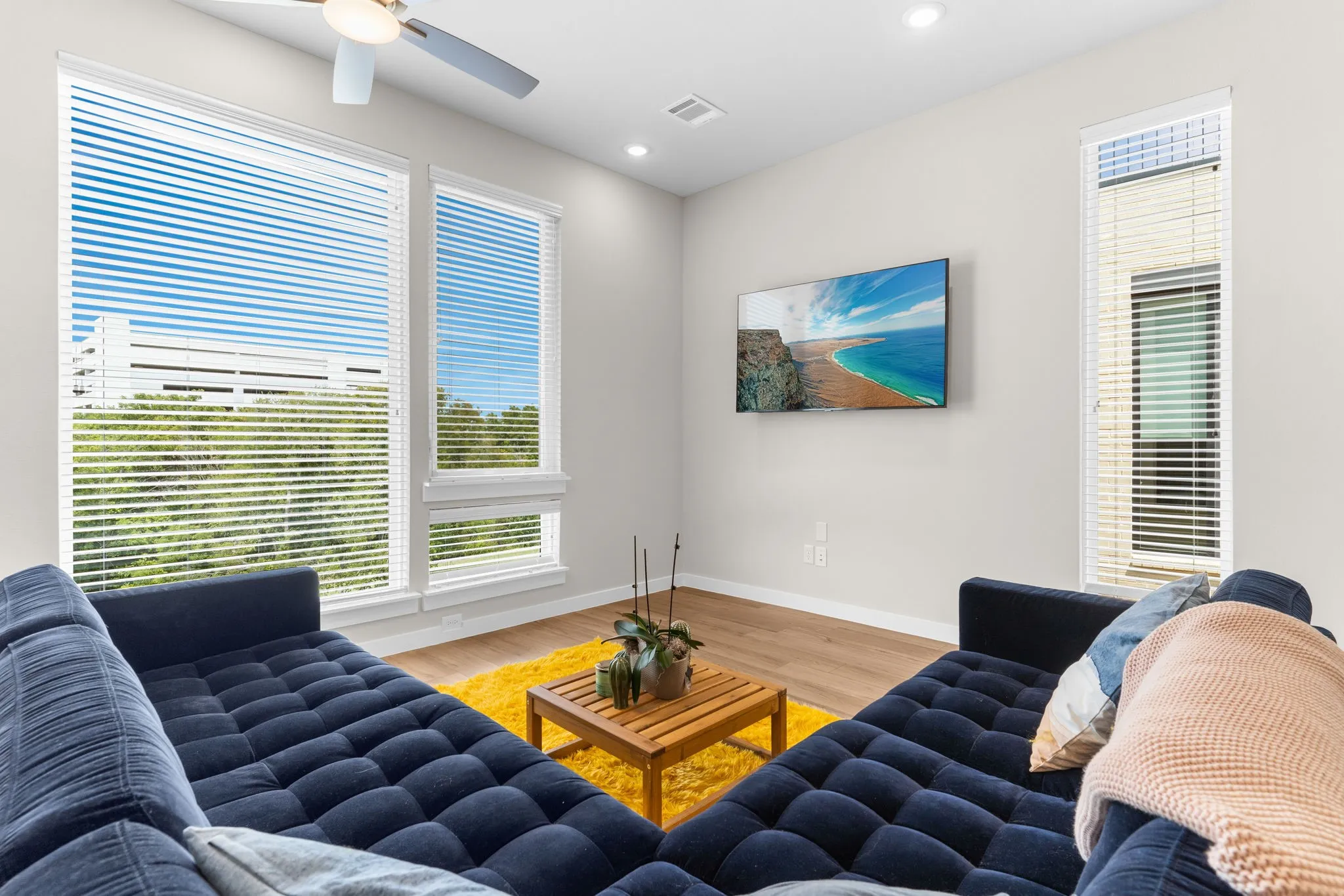 Large windows with blinds, wood-finish flooring, recessed lighting, and a ceiling fan