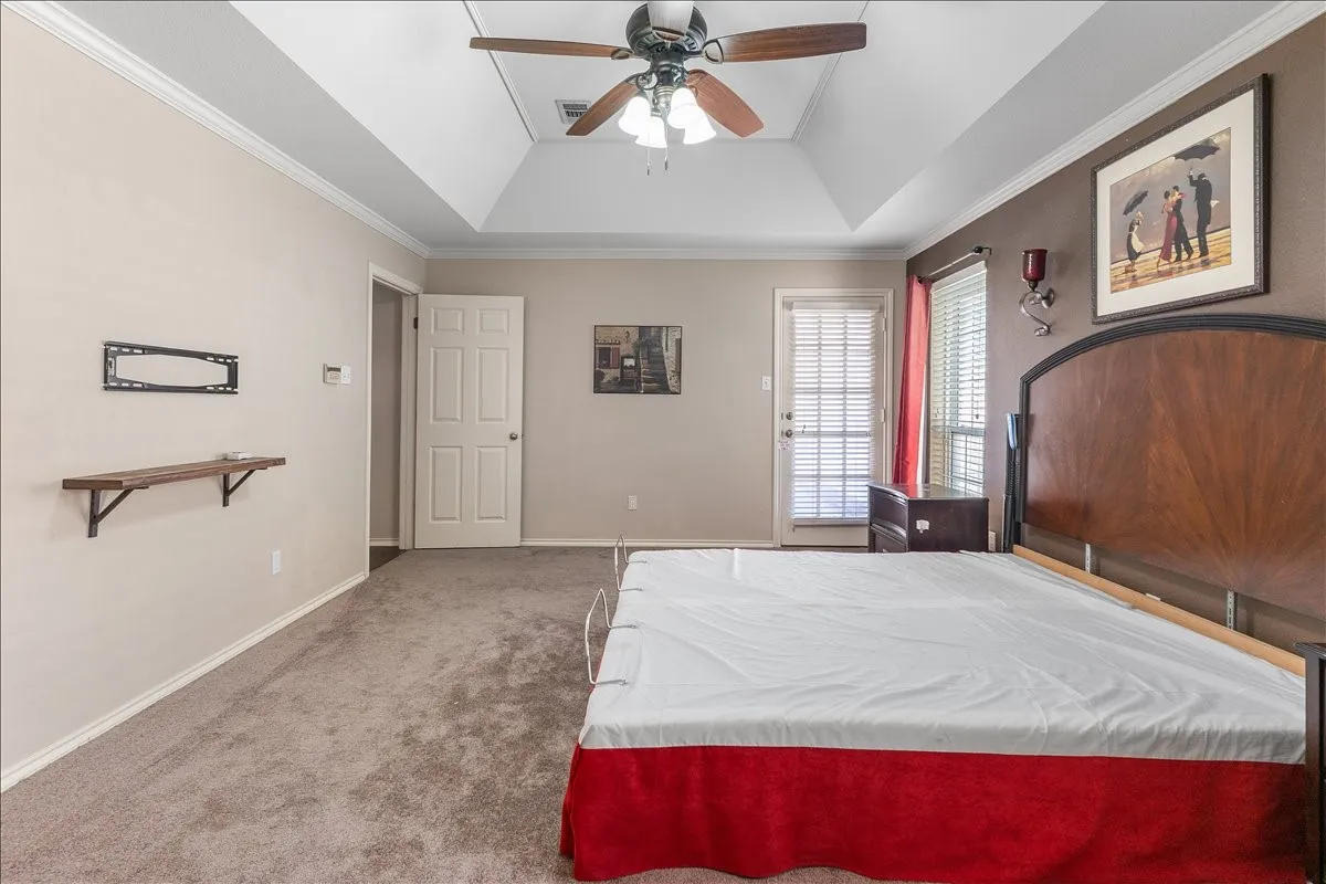 Vaulted ceiling with crown molding, ceiling fan, and wall-mounted sconce lighting