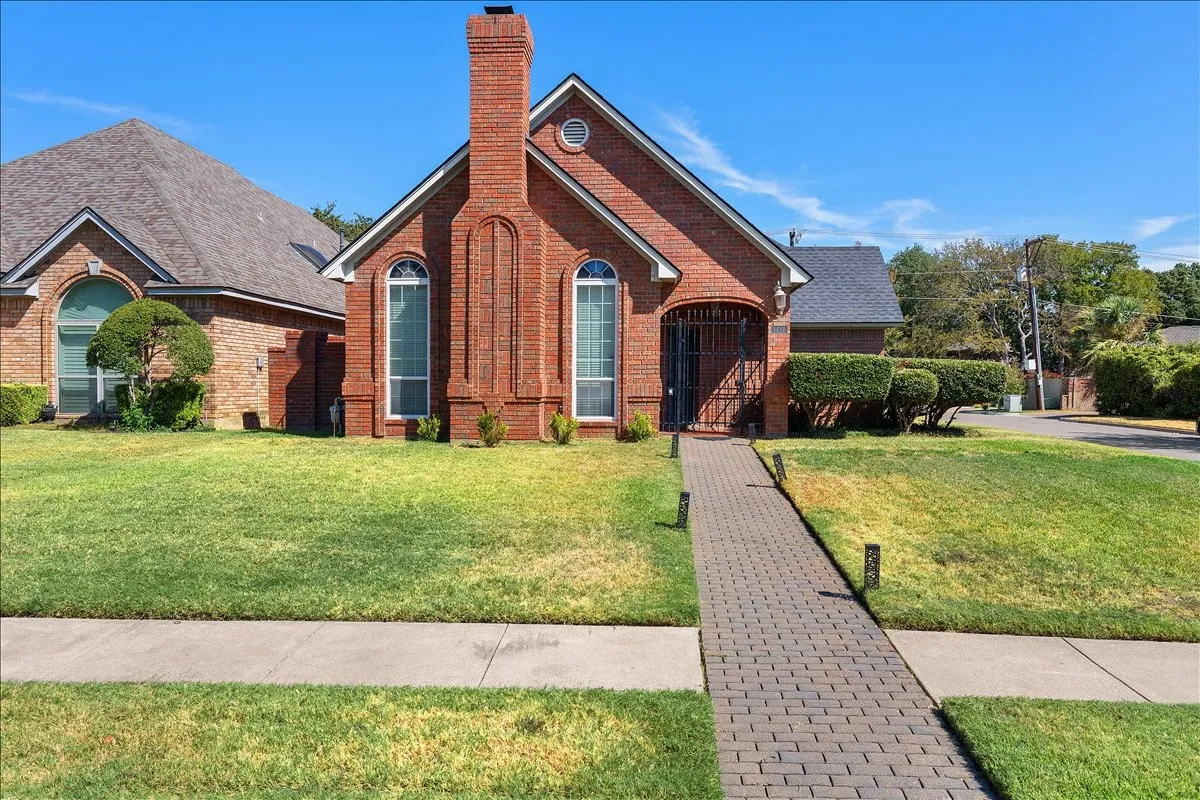 Brick exterior with arched windows, prominent chimney, and a stone-paved walkway