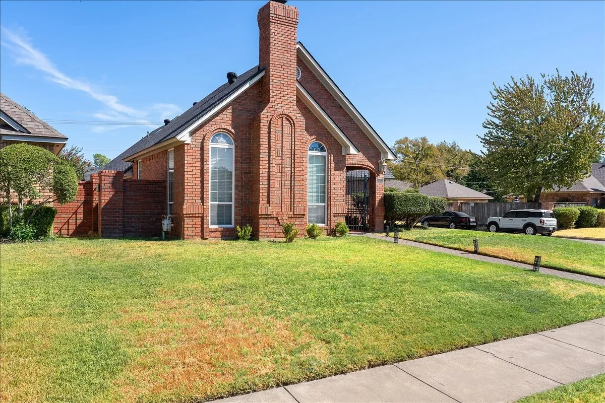 Brick exterior with a prominent chimney feature, arched windows, and a dark shingle roof