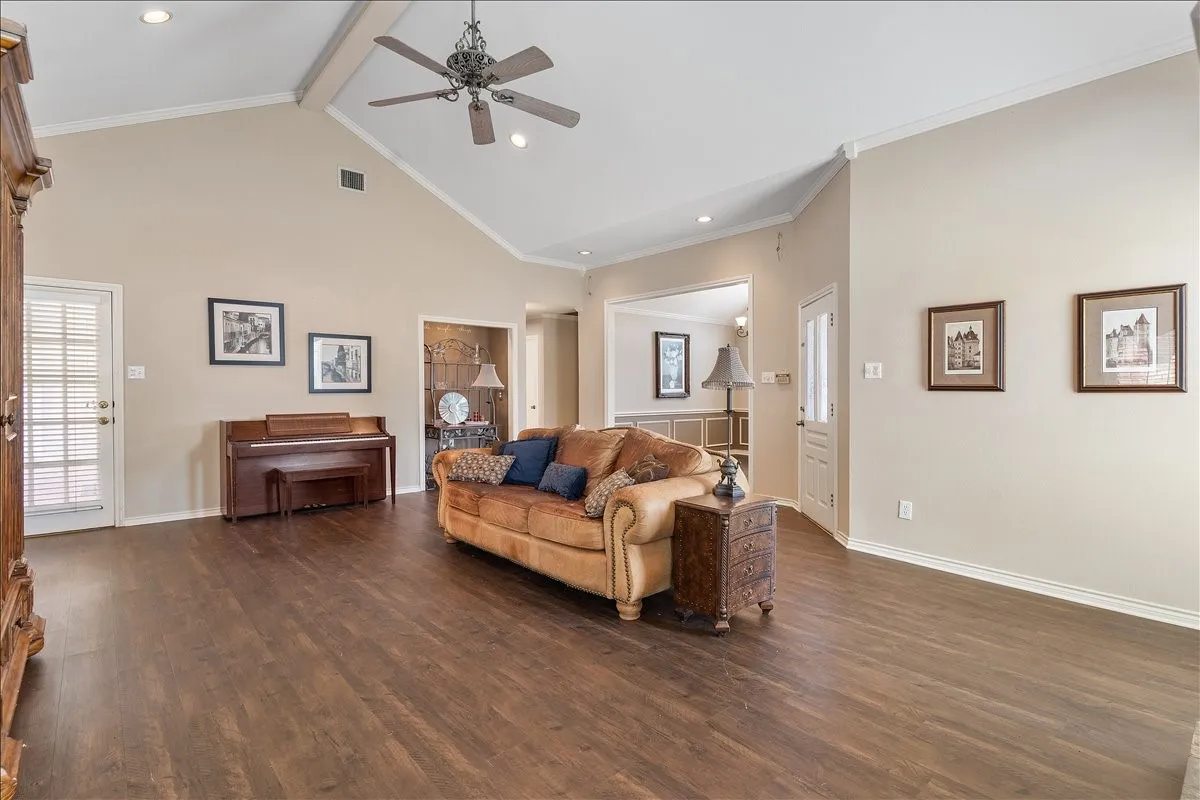 Vaulted ceiling with a ceiling fan, recessed lighting, wood-finish flooring, and white trim