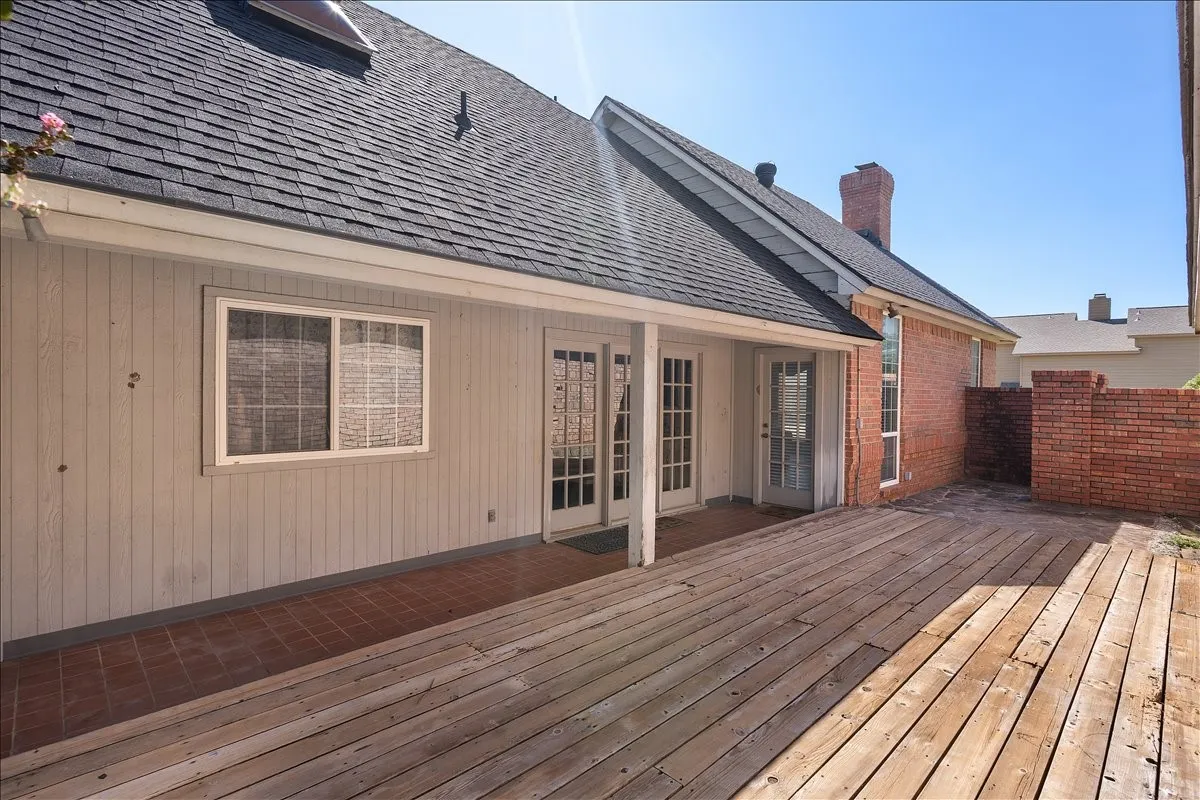 Expansive wood deck with a covered patio area and brick-finish privacy walls