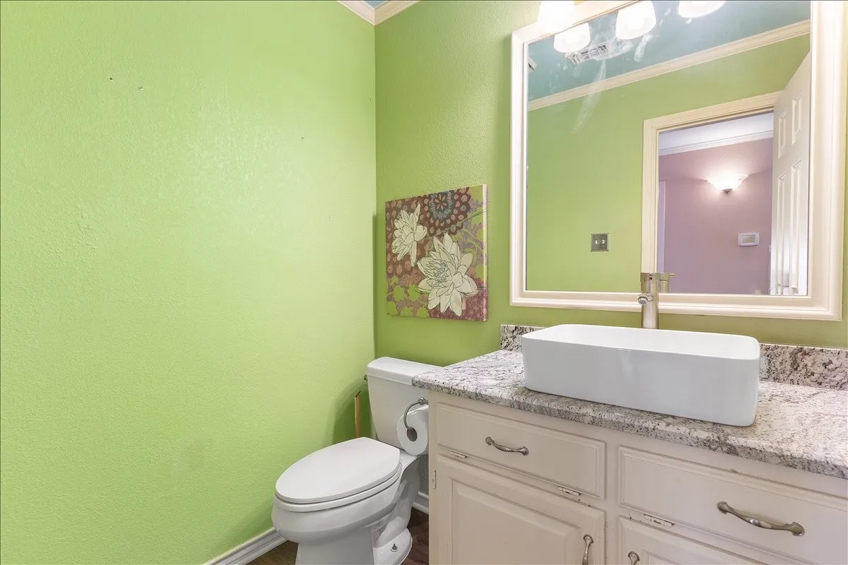 Vanity with granite countertop, vessel sink, and silver-tone faucet