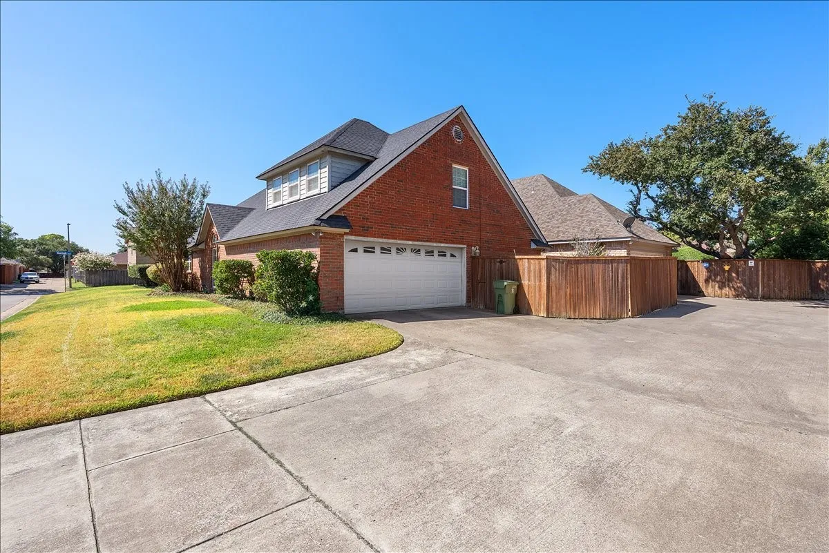 Brick exterior with a dormer window, attached garage, and concrete driveway