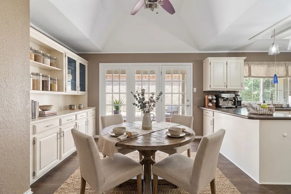 Vaulted ceiling, wood-finish flooring, built-in cabinetry with glass-front uppers, French doors, and breakfast bar