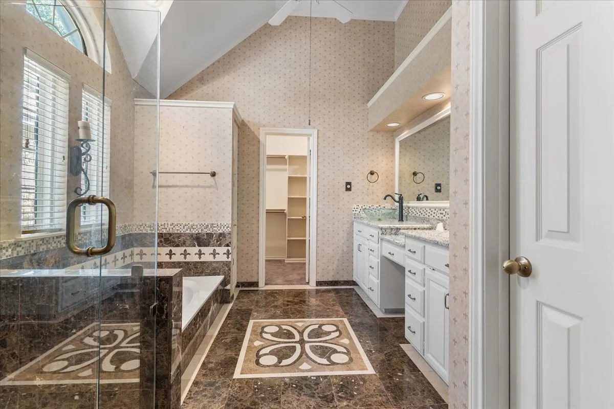 Expansive bathroom featuring a glass-enclosed shower, built-in soaking tub, dual vanity with undermount sinks, and patterned floor tile