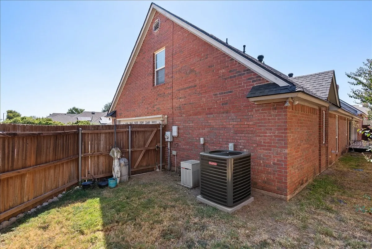 Red brick exterior with white trim, a gabled roofline, and a brown wood fence