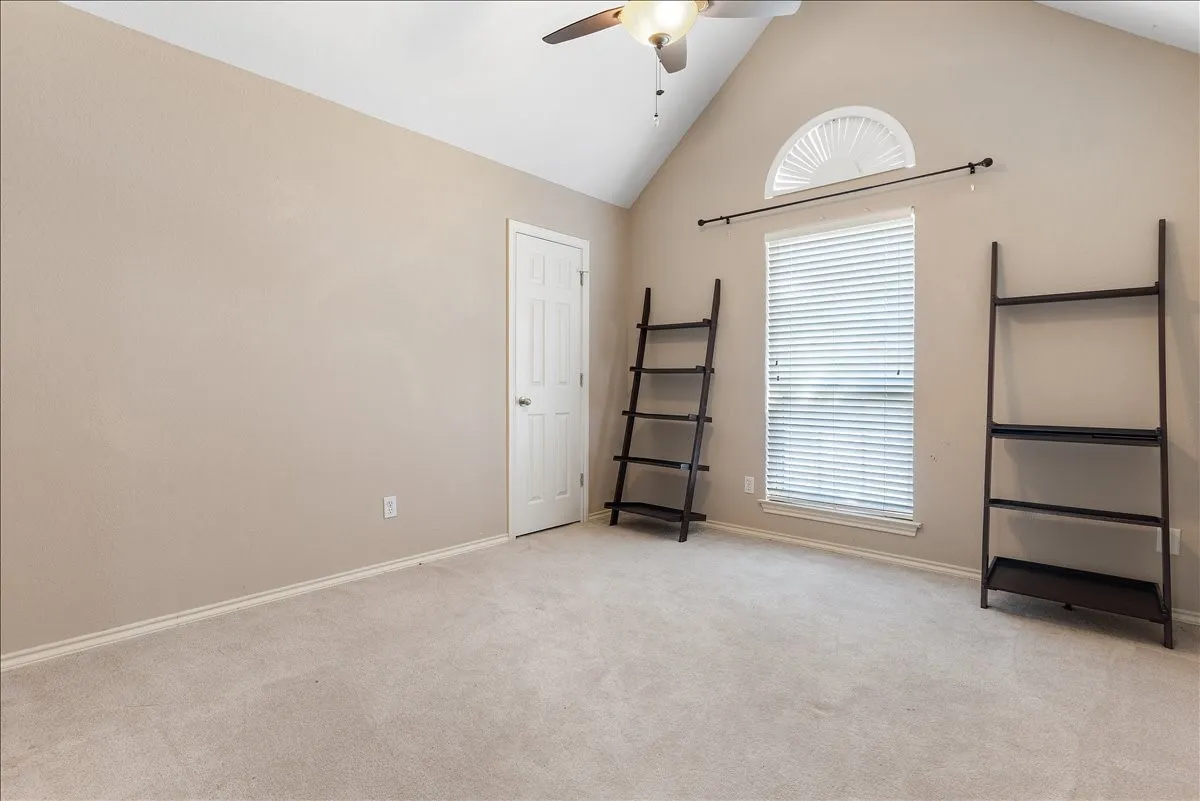 Vaulted ceiling with ceiling fan, arched window, rectangular window with blinds, and neutral carpet flooring