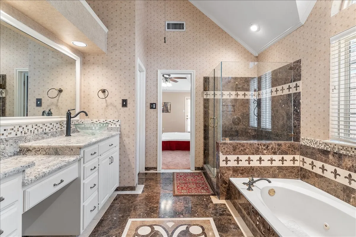 Bathroom featuring a glass vessel sink, granite-style countertops, a walk-in shower with tiled walls, a soaking tub, and a vaulted ceiling
