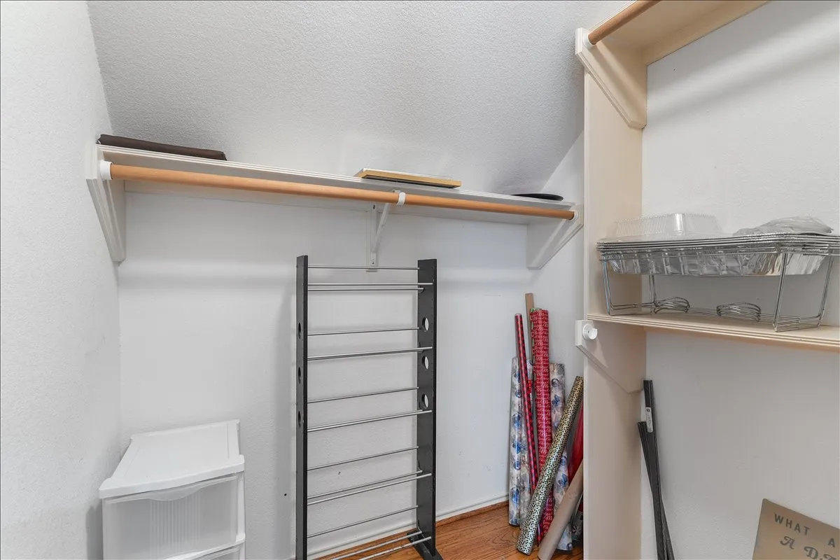 Closet with white walls, wood-finish flooring, and built-in shelving