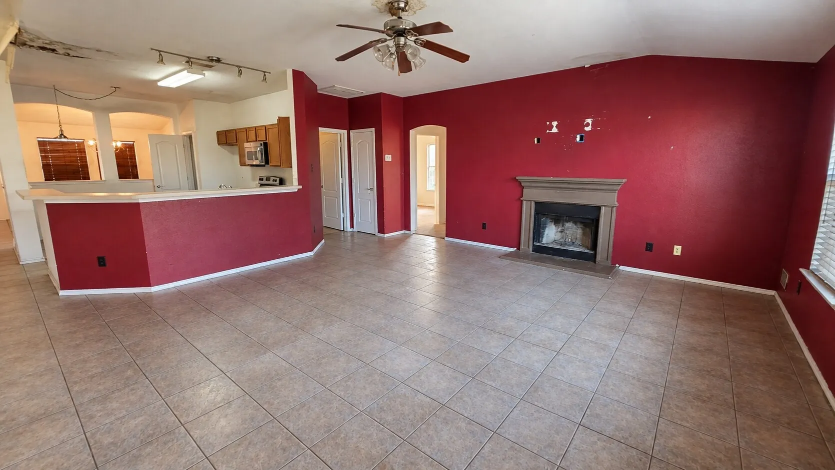 Tile flooring throughout, recessed archways, wood-finish cabinetry, built-in microwave, and a fireplace with a stone surround