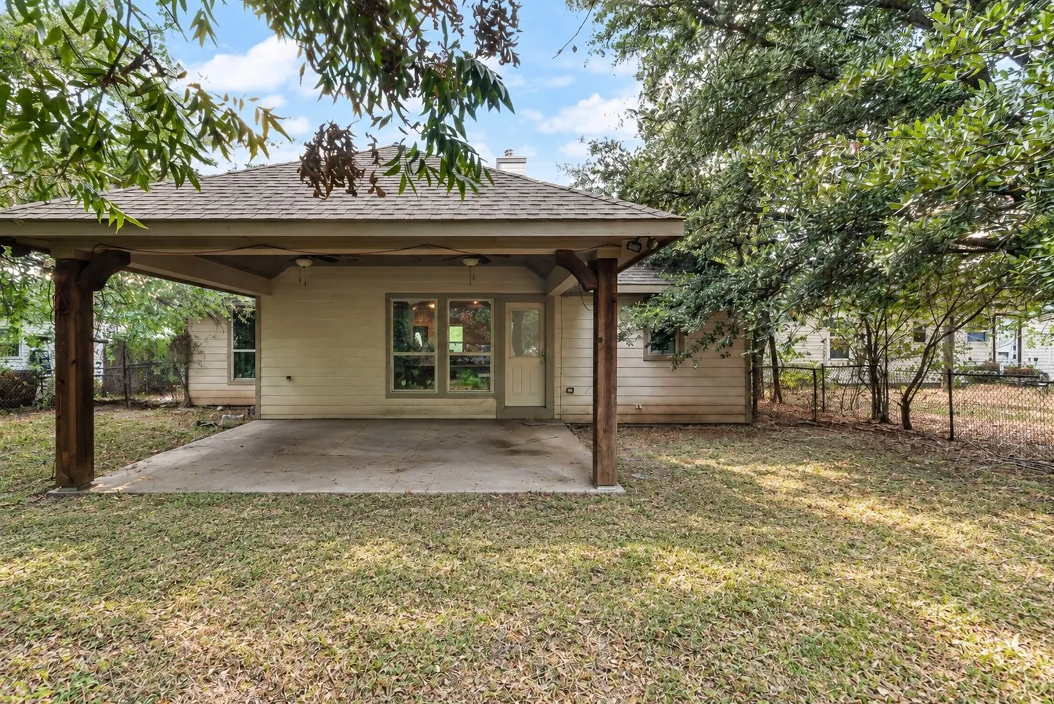 Covered patio with a concrete slab, wood support columns, and an exterior door