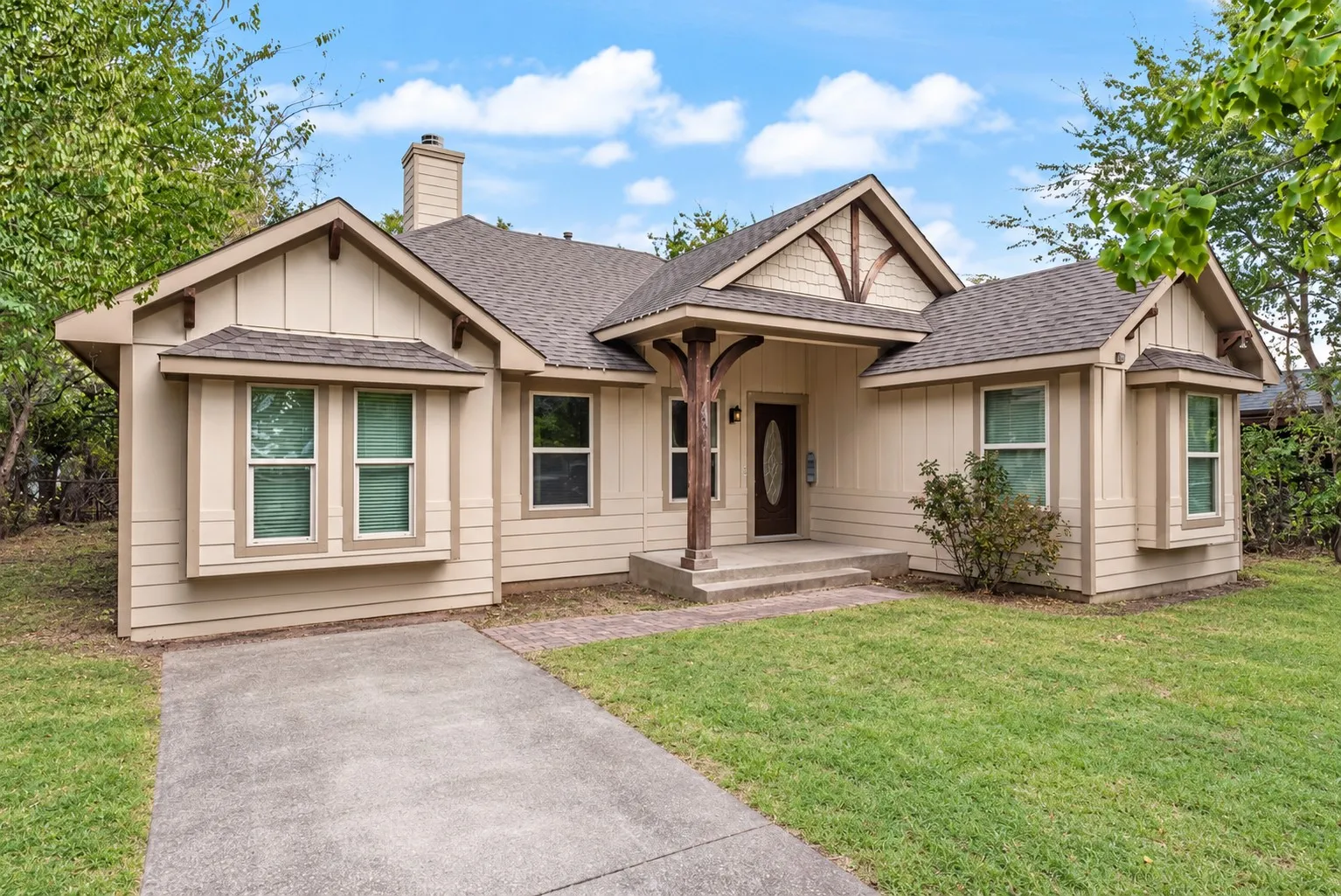 Exterior featuring a covered entry, decorative wood columns, multiple bay windows, and a concrete driveway