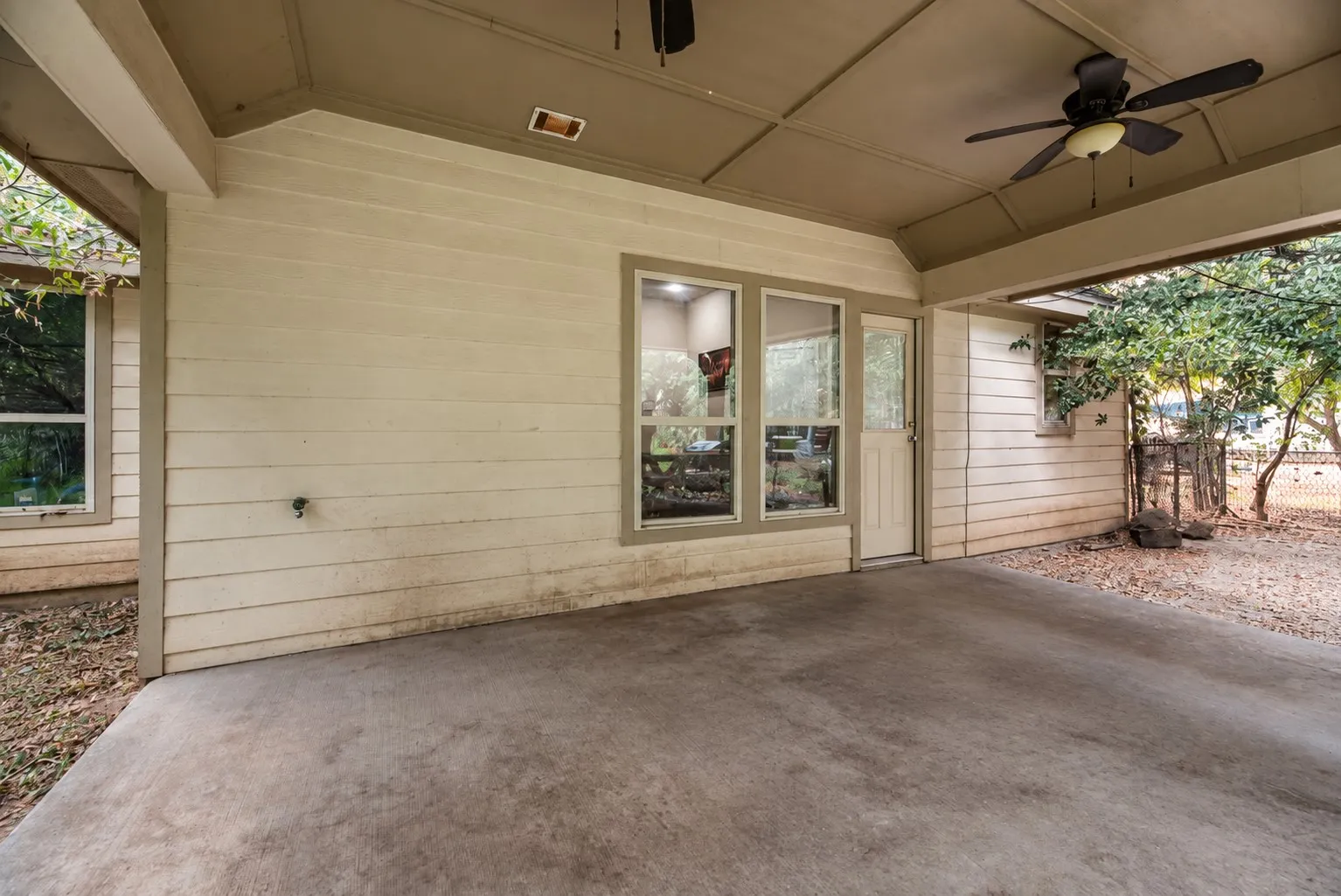 Covered patio with a concrete surface, a ceiling fan with integrated lighting, and multiple windows