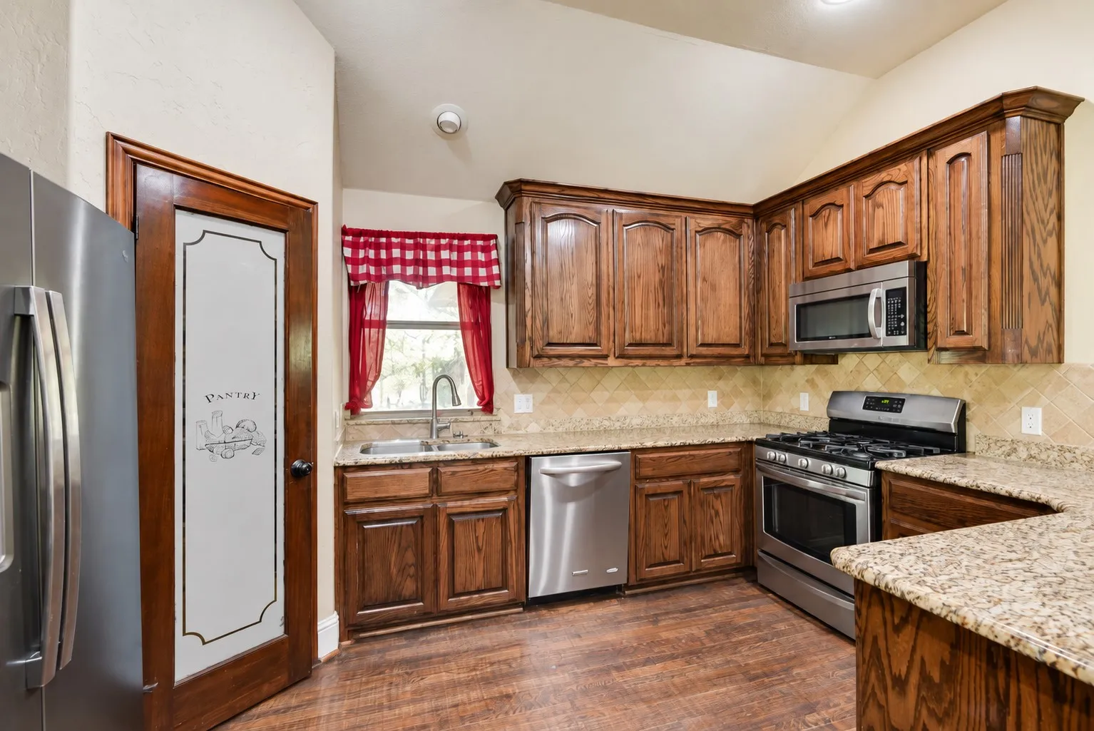 Kitchen featuring wood-finish flooring, granite countertops, and wood cabinetry