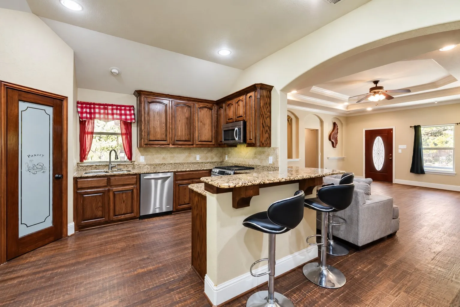 Kitchen with wood-finish flooring, dark wood cabinetry, granite countertops, and stainless steel appliances