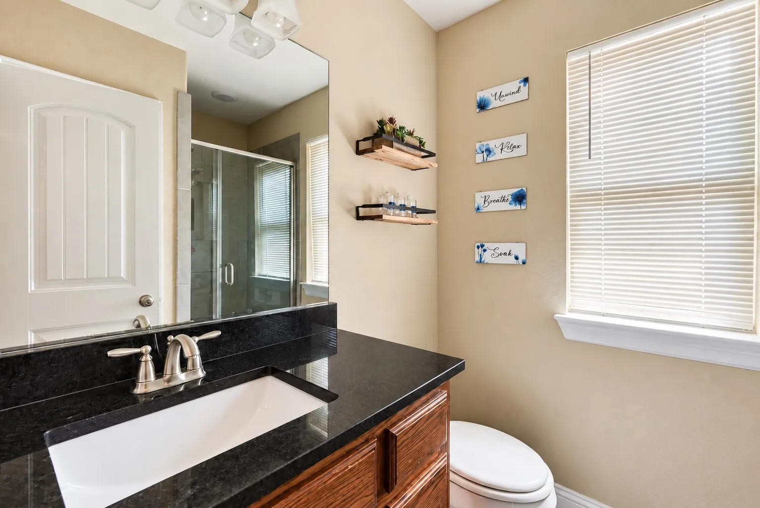 Vanity with dark countertop, integrated sink, and brushed nickel faucet