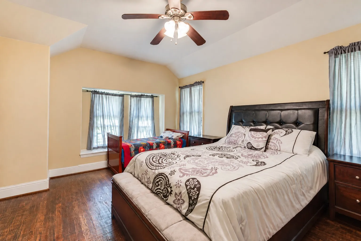 Wood-finish flooring, vaulted ceiling, and ceiling fan with integrated lighting