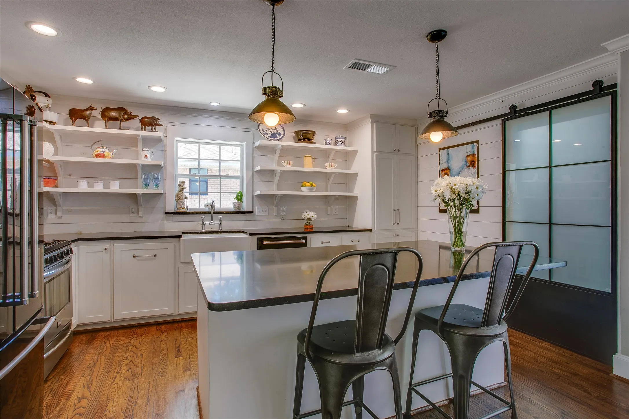 Kitchen features updated appliances, honed granite counters, open shelving and farm sink.