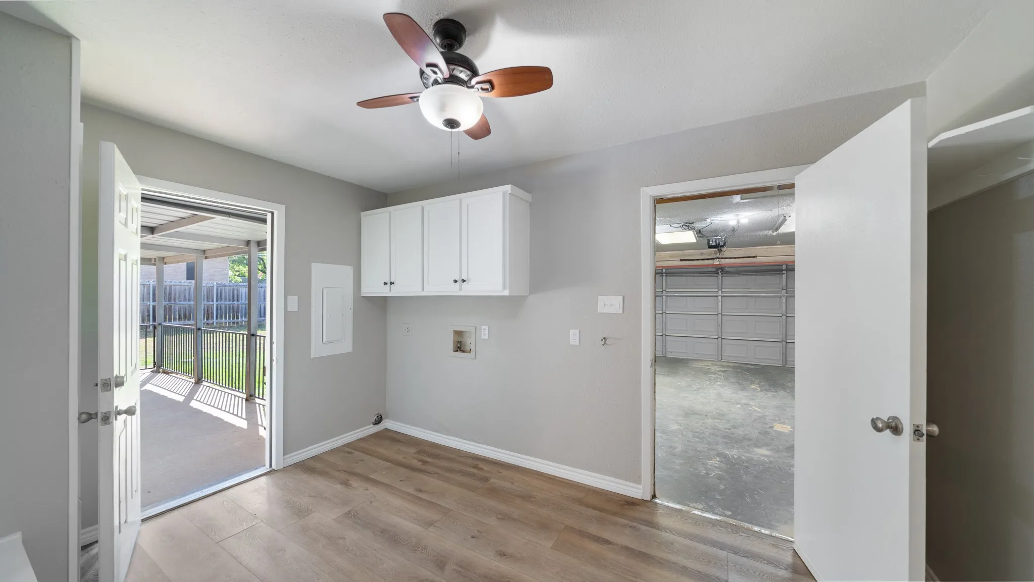 Wood-finish flooring, overhead cabinetry, ceiling fan, and access to an outdoor covered patio