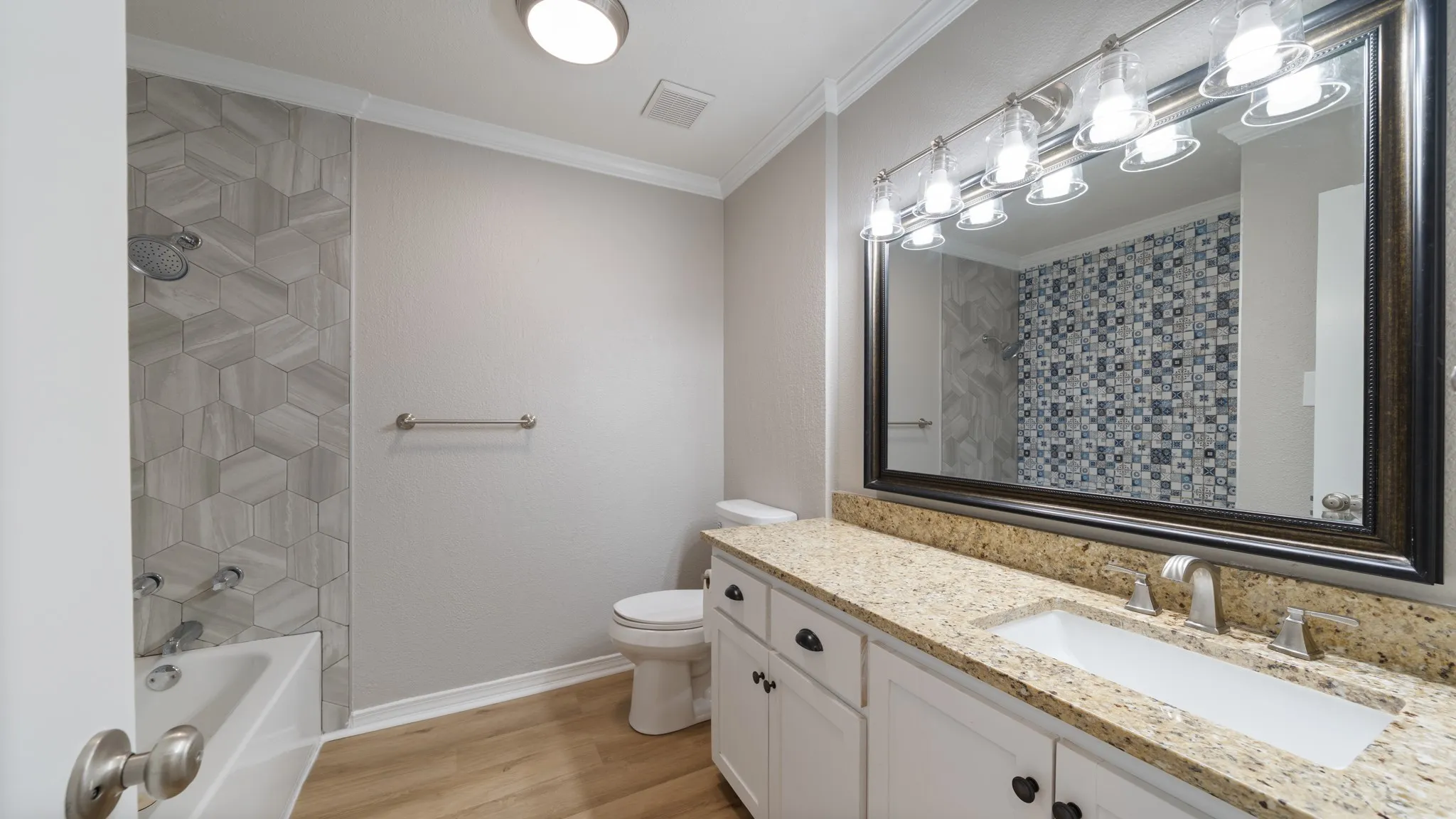 White vanity with black hardware, granite-style countertop, and integrated sink