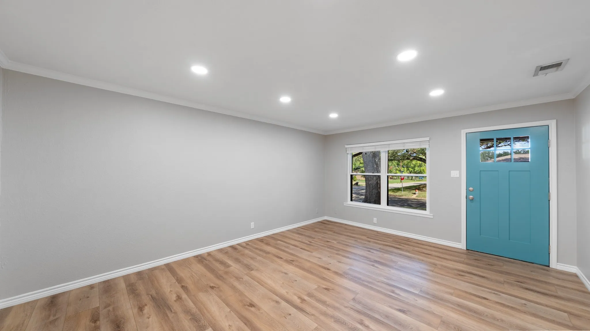 Wood-finish flooring with white trim and crown molding
