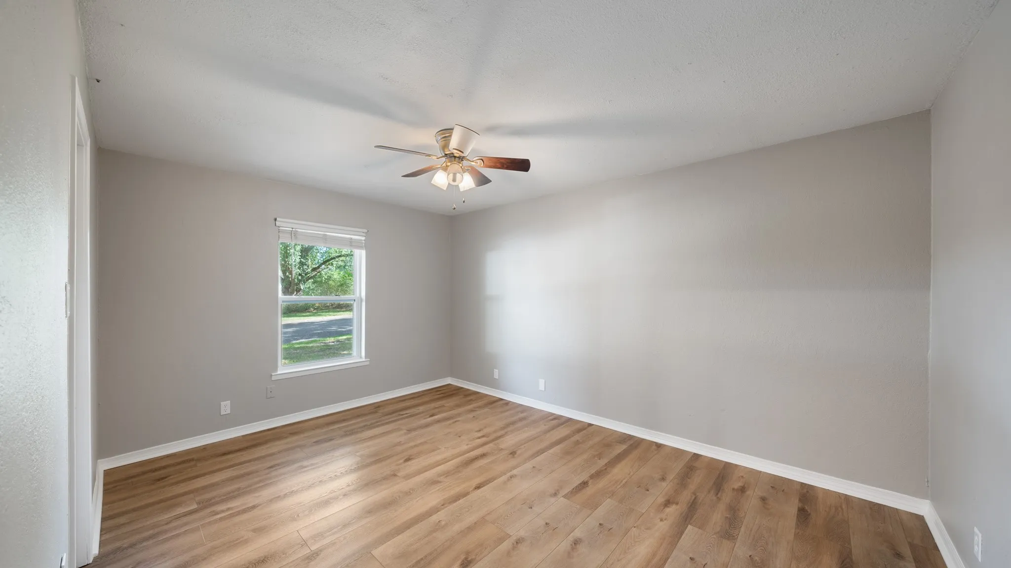 Bright interior with wood-finish flooring, light neutral wall paint, and a ceiling fan