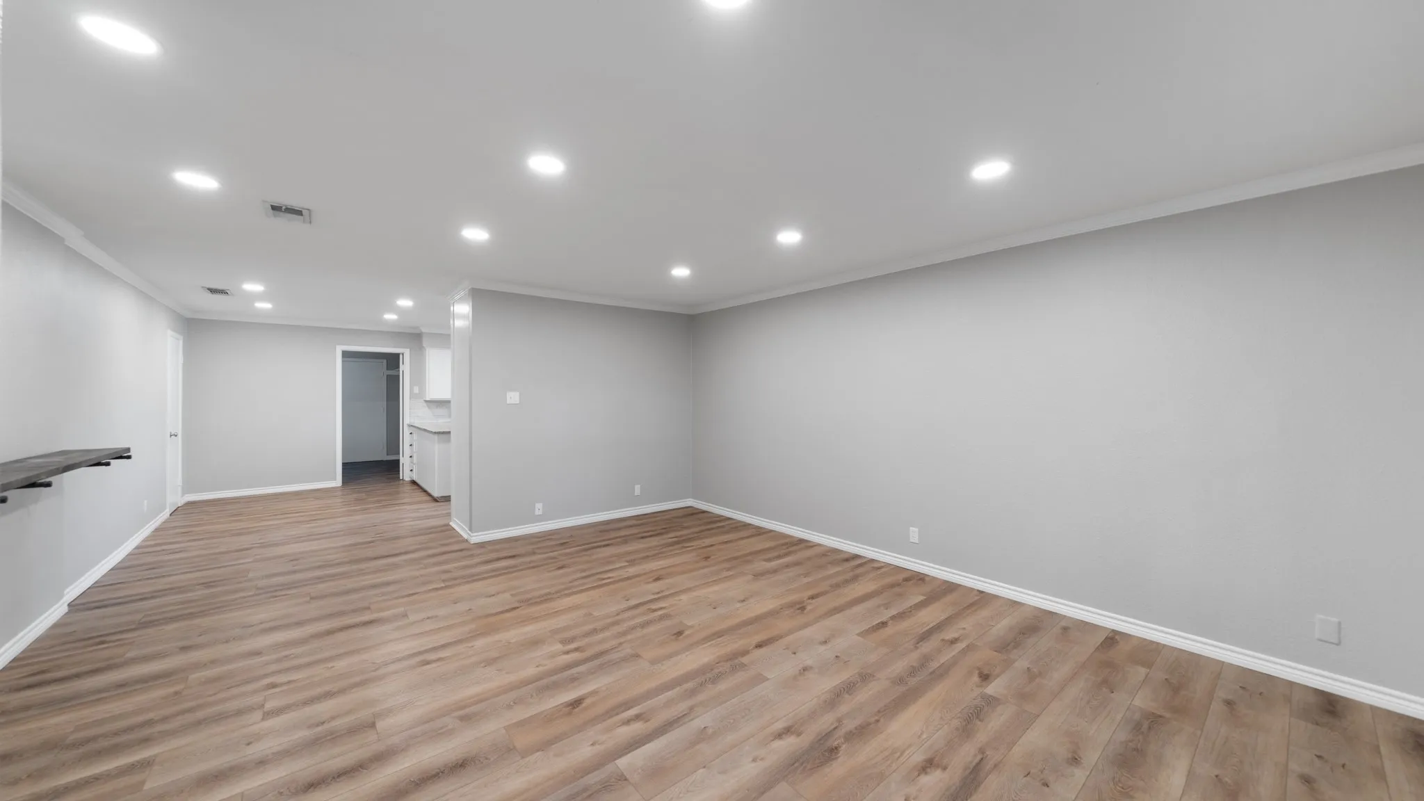 Spacious interior featuring wood-finish flooring, recessed lighting, crown molding, and neutral wall tones