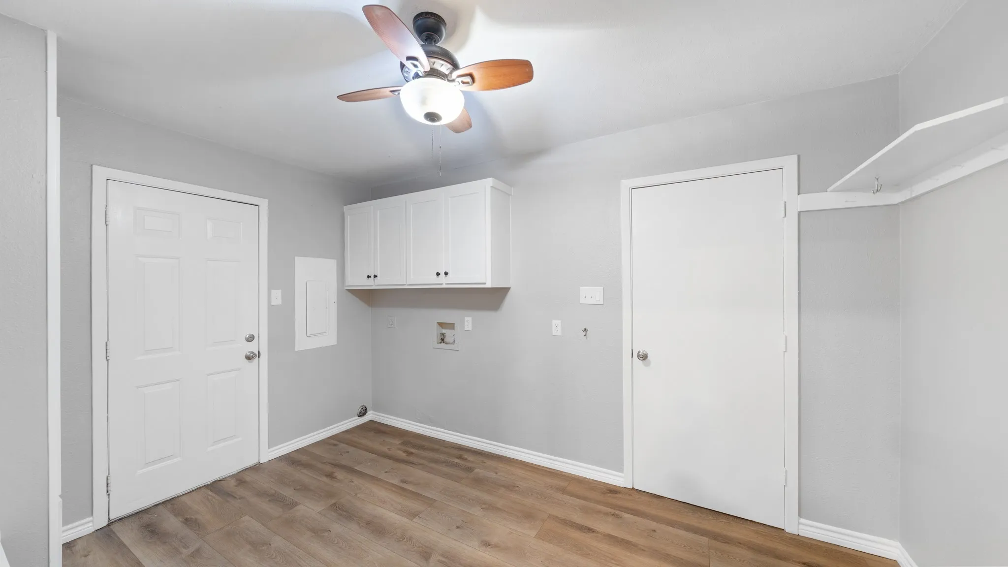 Wood-finish flooring, overhead ceiling fan with lighting, and white upper cabinetry