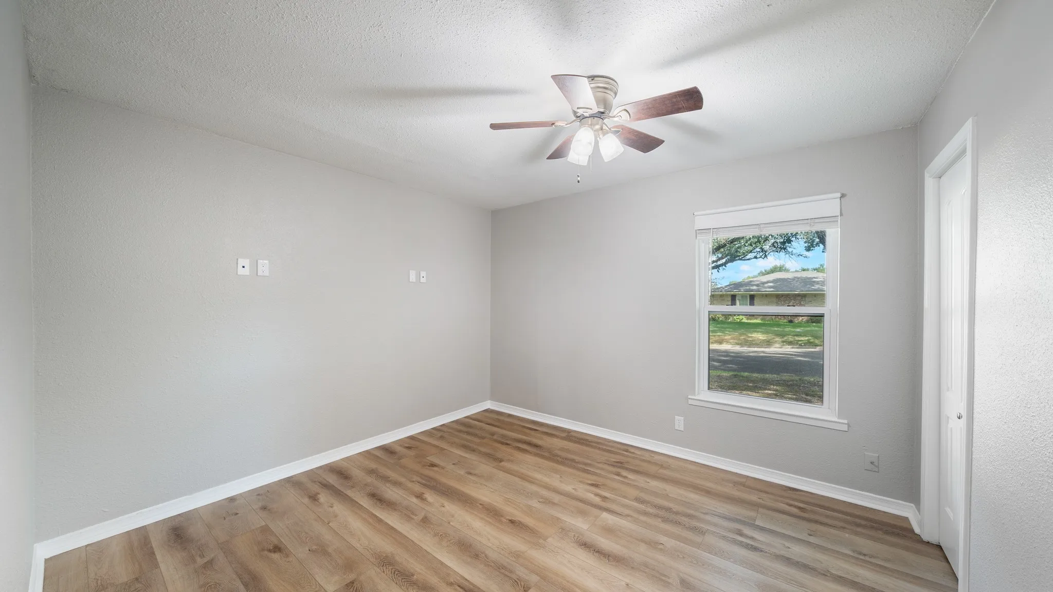 Wood-finish flooring, ceiling fan, natural light, and a white paneled door