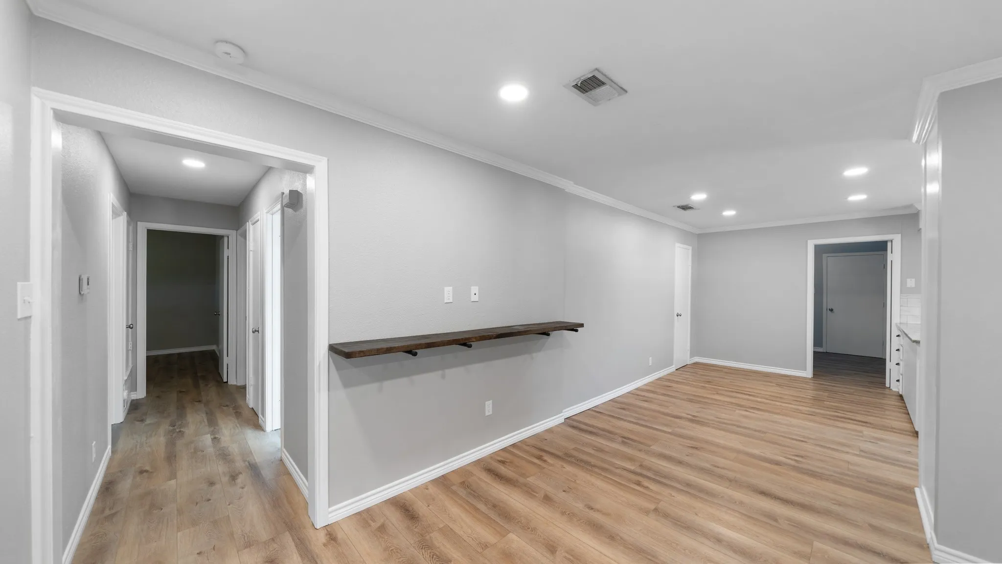 Wood-finish flooring, recessed lighting, crown molding, and a built-in wall shelf