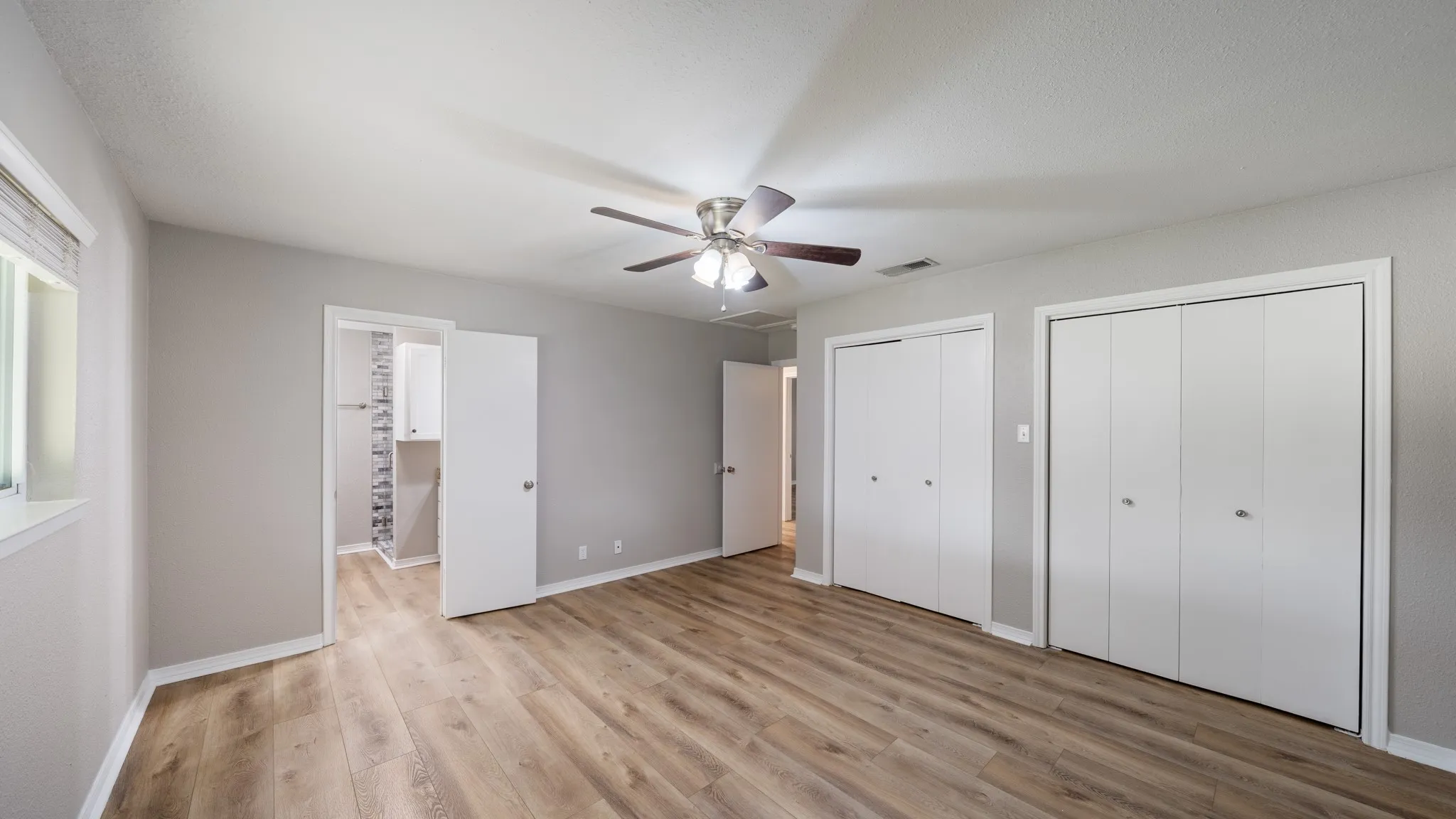 Wood-finish flooring, ceiling fan, and multiple closets with bi-fold doors