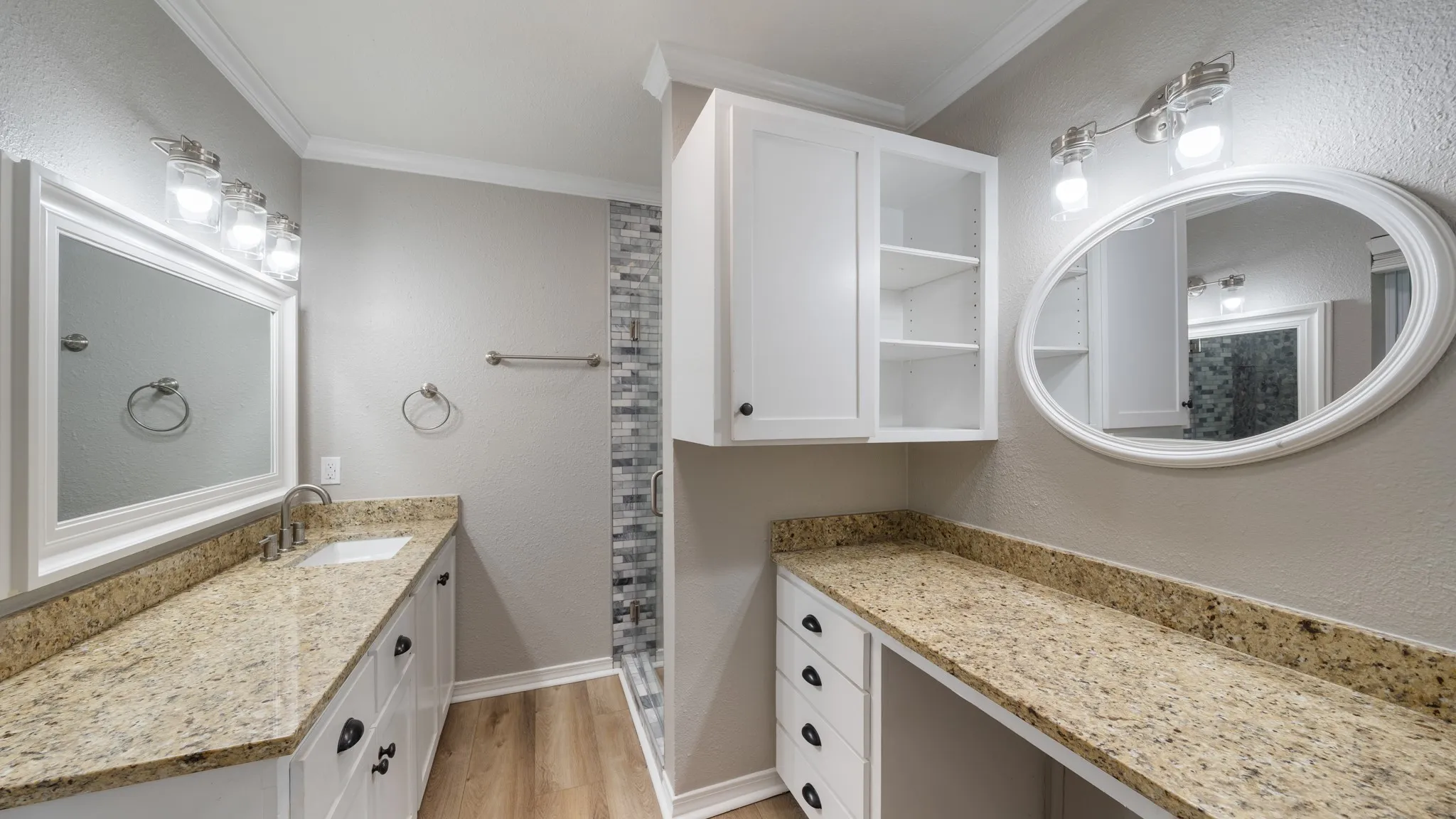 Dual vanity with white cabinetry, gold-flecked countertops, and wood-finish flooring