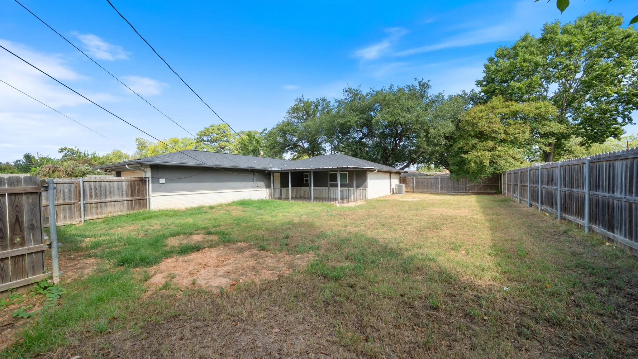 Expansive grass lawn, wood privacy fencing, screened porch, and mature trees