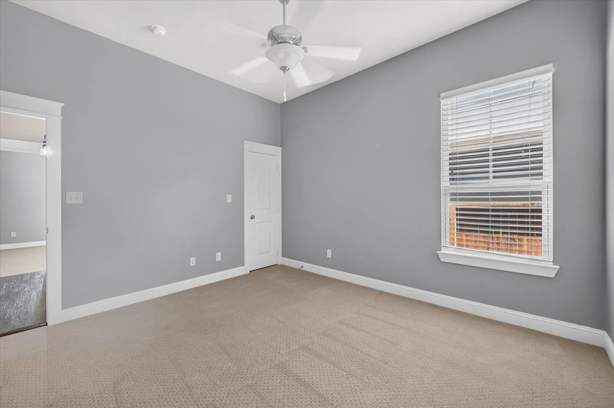 Neutral gray wall color, carpeted flooring, white trim, and a ceiling fan