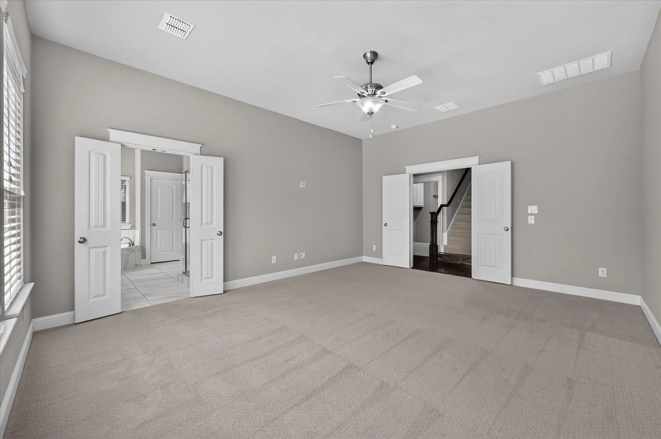 Spacious room featuring neutral carpet, light gray walls, a ceiling fan, and white trim