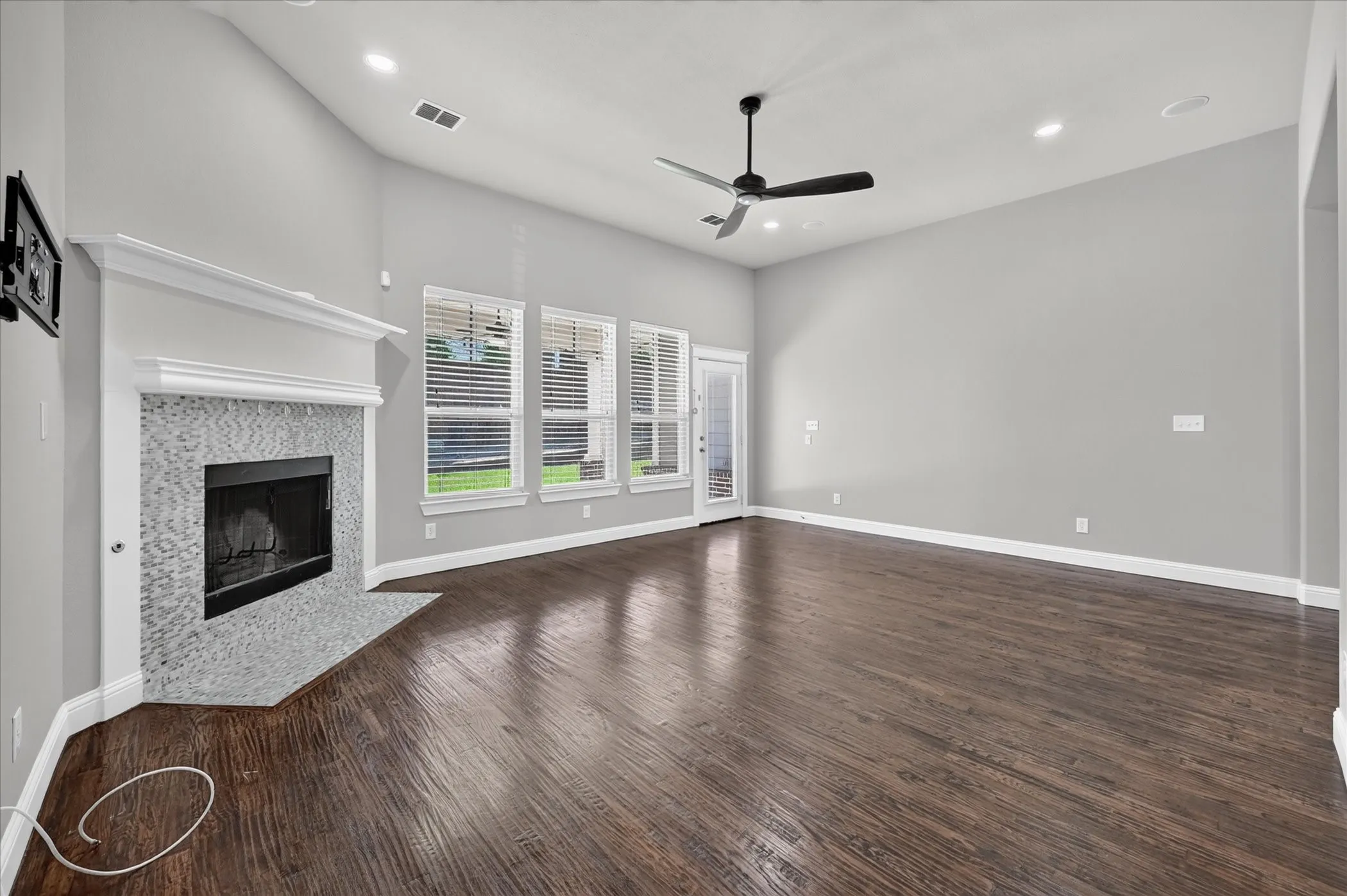 Spacious living area featuring high vaulted ceilings, elegant wood-finish flooring, a contemporary ceiling fan, and recessed lighting